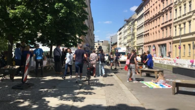 Eine Straßenszene mit spielenden Kindern auf der Straße und in Ruhe flanierenden Passanten.